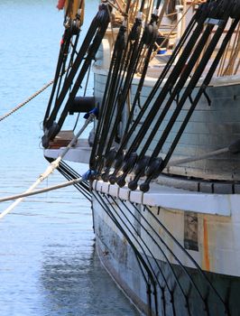 rigging of a sail boat with the blue water in the background