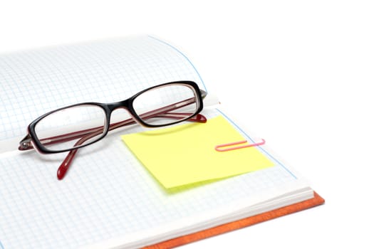 Spectacles on note pad with yellow bookmark and rose staple