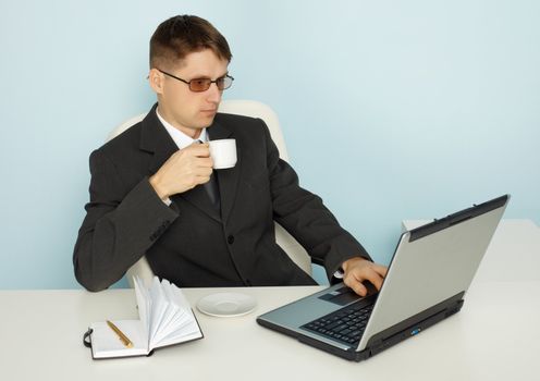 Business man reads the news online and drinking coffee