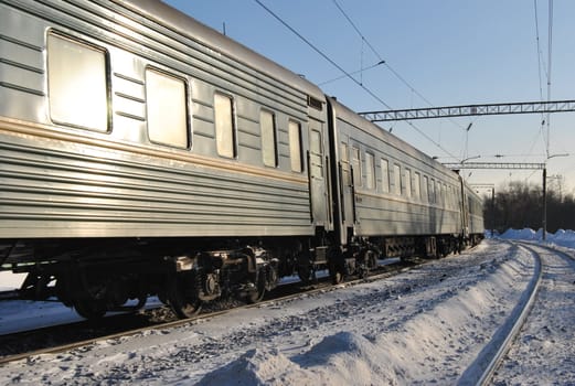 A passenger train travels on a snowy winter rail