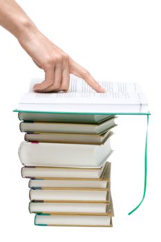 Openning book on pile of the books, hand points to text