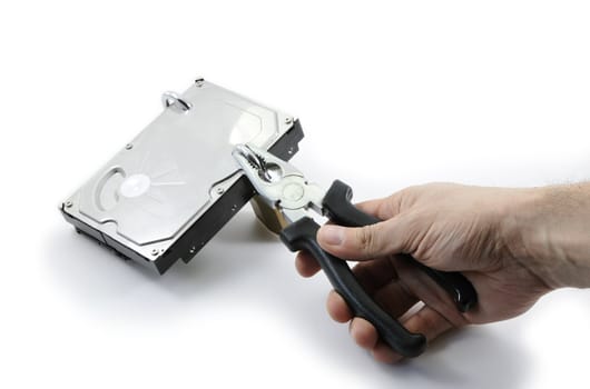 Hard disk locked under attack by one hand with pliers on a white background
