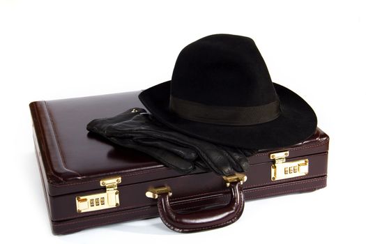 Suitcase with laying from above a hat and gloves on a white background
