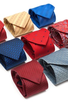 Varicoloured male ties convolute on white background