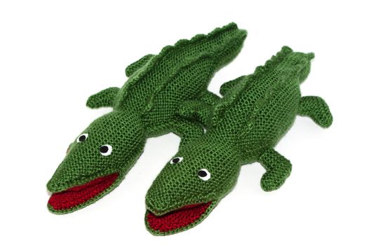 Pair of green crocodiles homemade knitted toy on white