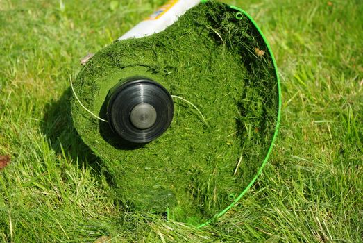 Lawntrimmer after work on green grass in garden