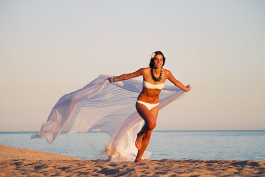 View of a beautiful young girl with a white bikini running on the beach.