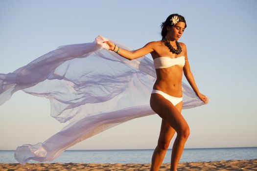 View of a beautiful young girl with a white bikini running on the beach.