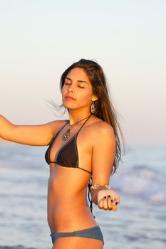 View of a beautiful young girl with a bikini standing on the shore.