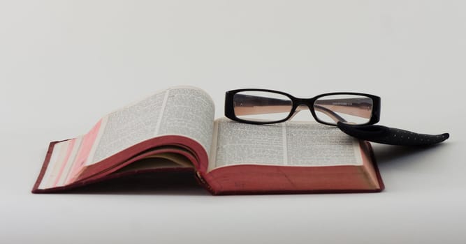 A pair of reading glasses resting on the bible.