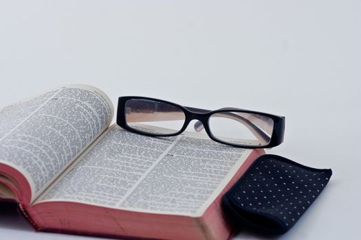 A pair of reading glasses resting on the bible.