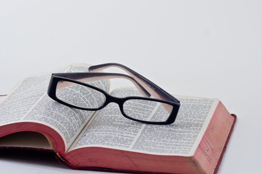 A pair of reading glasses resting on the bible.