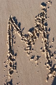 Letter M drawn in the sand.