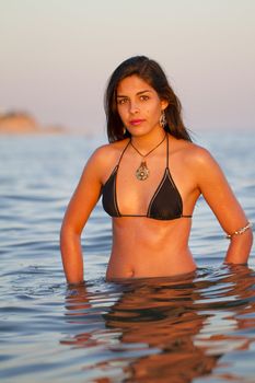 View of a beautiful young girl with a bikini standing on the shore.