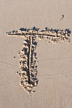 Letter T drawn in the sand. 