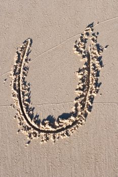 Letter U drawn in the sand.