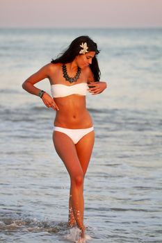 View of a beautiful young girl with a bikini standing on the shore.