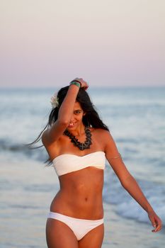 View of a beautiful young girl with a bikini standing on the shore.