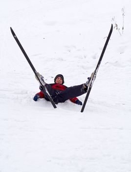 boy is resting in the snow skis sticking up