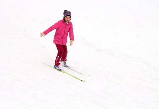 Little girl skiing fast down the hill in snow winter day