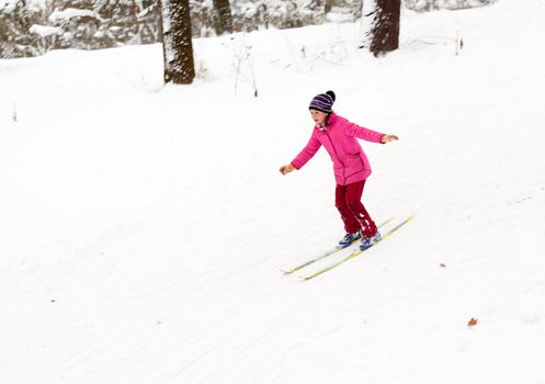 Little girl skiing fast down the hill in snow winter day