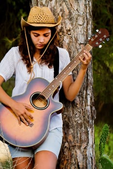 View of a beautiful young country girl with a guitar on the woods. 