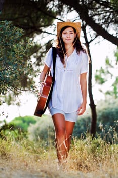 View of a beautiful young country girl with a guitar on the woods. 