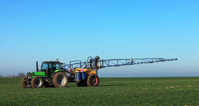 A tractor spreading substances in the early spring in a field in Central region of France.
