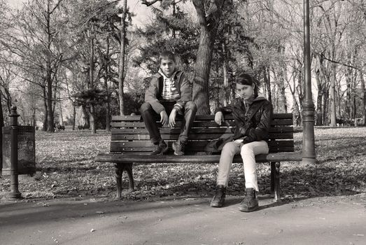 caucasian teenage girl and boy on bench in park, black and white