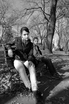 Teenage girl and boy on bench in park, black and white