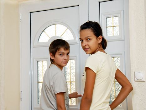 teenage girl and boy by white front door smiling