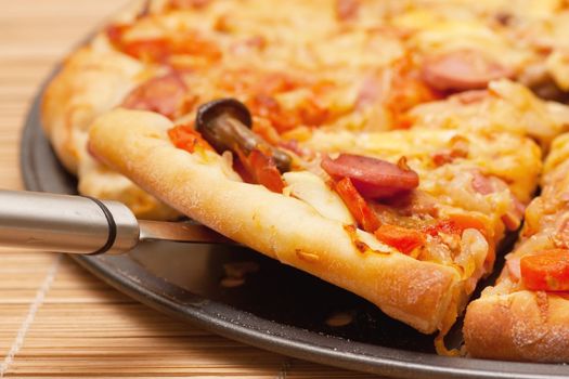 A slice of pizza is lifted from the pan with a spatula