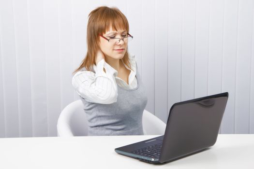 tired worker in the office. Disheveled girl with laptop. neck pain
