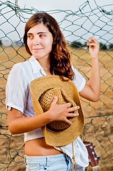 View of a beautiful young country girl with a guitar on the fence of the grassland. 