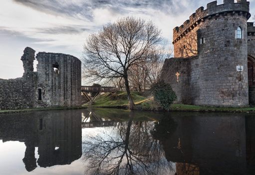 Ancient Whittington Castle in Shropshire, England reflecting in a calm moat round the stone buildings