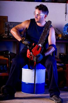 View of a garage mechanic man holding a chainsaw.