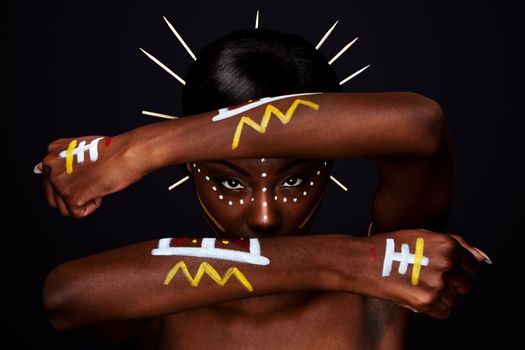 Beautiful cultural tribal African female face with arms and hands in fron, yellow, red and white makeup cosmetics lines dots, sticks in hair.