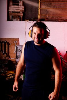 View of a garage mechanic man smiling with protective headphones.