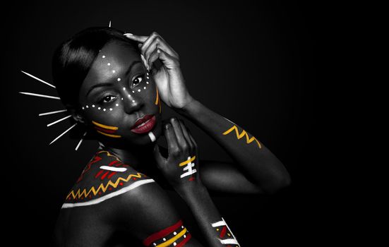 Beautiful exotic African female fashion face with tribal yellow red and white makeup cosmetics and sticks in hair.