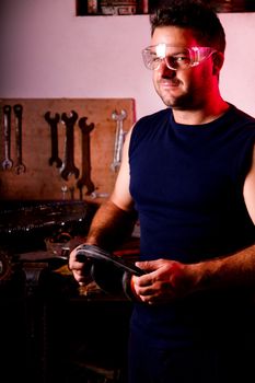 View of a garage mechanic man smiling and holding some protective headphones.