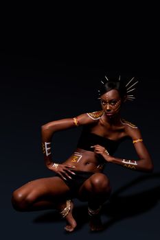 Beautiful exotic African female fashion with tribal yellow red and white makeup cosmetics and sticks in hai, in dance position.