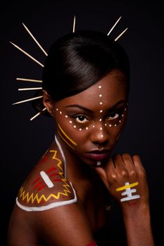 Beautiful exotic African female fashion face with tribal yellow red and white makeup cosmetics and sticks in hair.