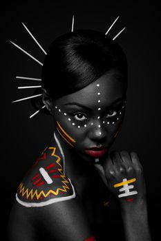 Beautiful exotic African female fashion face with tribal yellow red and white makeup cosmetics and sticks in hair.