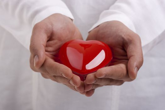Man in white holding a red heart in his hands.