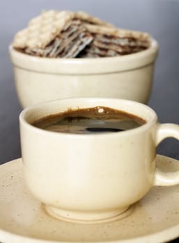 Cup of strong black coffee with waffles on a table