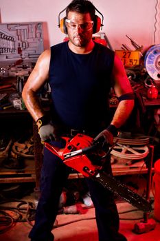 View of a garage mechanic man holding a chainsaw.