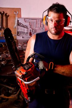 View of a garage mechanic man holding a chainsaw.