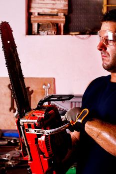 View of a garage mechanic man holding a chainsaw.