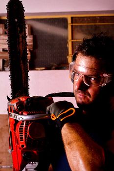 View of a garage mechanic man holding a chainsaw.