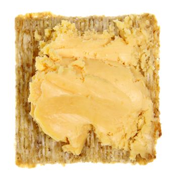 A square whole wheat cracker with cheese isolated on white.
